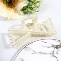Detailed view of cream bow-shaped hair claw clip with pearls and golden spring mechanism - Bow Tie