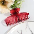 Detail of red translucent shark hair claw clip with sturdy teeth on marble surface - Red
