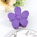 Close-up of a purple matte flower hair claw clip on a white marble texture tray - Purple