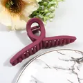 Detail of large matte dark pink hair claw clip on marble tray with floral accents - Burgundy