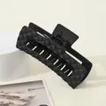 Macro view of a large matte black hair claw clip featuring a 3D diamond quilted pattern - Black