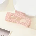 Detailopname van roze matte haarklem met een elegant gewatteerd ruitjespatroon - Lichtroze