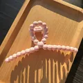 Detail of pink bubble texture hair claw clip on wooden tray with aesthetic shadows - Pink
