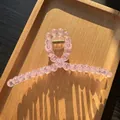 Pink matte bead shark hair clip with gold metal spring on a light wood tray - Transparent Pink