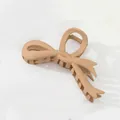 Close-up of matte beige bow hair claw clip showing textured plastic and spring detail - Light Coffee