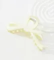 Detail of off-white bow hair claw clip with matte finish on decorative wave plate - Off-white