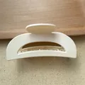 Close-up of a matte cream hair claw clip with non-slip teeth on a wooden tray - Ivory
