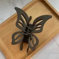 Matte brown butterfly hair claw clip with cutout design on a wooden tray - Dark Coffee