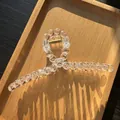 Detail of a large clear beaded hair claw clip with golden spring on a wooden tray - Clear