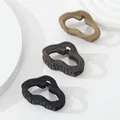 Close-up of three matte hair claws in brown and black with wavy geometric design - Earth Tone Irregular (404)