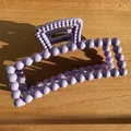 Detailed view of large matte purple bead-shaped hair claw clip on a wooden surface - Violet