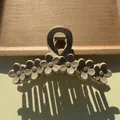 Detail of matte beige flower hair claw clip with floral pattern on a wooden tray - Dark Coffee