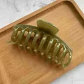 Dettaglio ravvicinato di una grande pinza per capelli verde oliva lucida - Verde