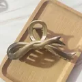 Detailed view of champagne gradient bow hair claw clip on a wooden display tray - Brown