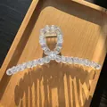 Detailed top view of transparent beaded hair claw with golden spring on wooden tray - Transparent Blue