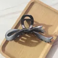 Detail of gradient grey bow hair claw clip with strong spring on a wooden tray - Gray-black Gradient