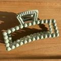 Close-up of mint green matte rectangle hair claw clip with round bead design on wood - Green