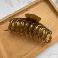 Dettaglio di un grande fermaglio per capelli verde oliva su vassoio in legno - Marrone