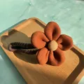 Detailed view of the fuzzy orange blossom hair clip on a wooden tray with soft textures - Orange Red