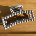 Macro detail of a grey matte rectangular claw clip with a stylish beaded frame design - Lavender