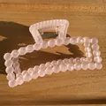 Gros plan d'une pince à cheveux carrée rose mat avec design à bulles sur bois - Rose