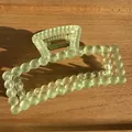 Detail view of large matte mint green bubble hair claw clip with golden spring on wood - Matte Green