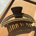 Detail einer khakifarbenen Haarklammer mit Blasenstruktur und mattem Finish auf Holz - Hellkaffee
