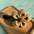 Detail of plush flower hair clip with soft khaki fabric petals and textured brown stamen - Brown