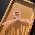 Close-up of a pink beaded hair claw clip with a golden spring on a wooden tray - Transparent Pink