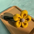 Detail einer gelben Plüschblumen-Haarspange mit grünem Griff auf Marmorhintergrund - Gelb