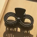 Close-up of black matte hair claw clip with beaded texture on a wooden background - Black