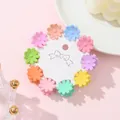 Close-up of ten colorful mini daisy hair clips arranged on a white card display - Daisy Style (A)