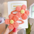 Detailed view of two handmade knitted coral pink flower hair clips for girls on display card - Knitted Texture Style / Orange