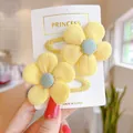 Close-up of cute yellow fabric flower hair clips on white card for girls hair styling - Fabric Style / Yellow