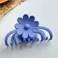Detailed view of large matte blue daisy flower hair claw clip on a rustic woven mat - Blue Style 1