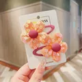 Detail of two orange mesh flower hair clips for girls on a white card board - Orange 2