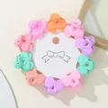 Macro detail of colorful bow-shaped mini hair claws on white round card packaging - Bow Tie