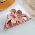 Detail shot of a matte pink flower hair claw clip on an orange plate and beige mesh - Light Pink