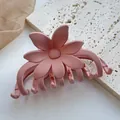 Nahaufnahme einer mattrosa Blumen-Haarklammer auf einer weißen Steinfläche - Mattierte 3D-Blume / Rauchrosa