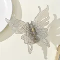 Detail of a translucent grey butterfly hair claw clip with a strong gold metal spring - Gray
