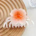 Macro shot of gradient orange resin flower hair claw clip on a textured wooden tray - White Orange