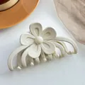 Détail d'une pince à cheveux fleur mate blanche sur une plaque décorative en céramique - Blanc