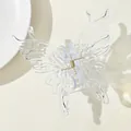 Macro view of translucent butterfly hair claw clip with gold metal spring detail - Clear
