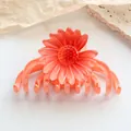 Macro detail of an orange daisy hair claw clip with gradient petals on a stone base - Orange Red