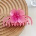 Close-up of a pink gradient floral hair claw clip on a wooden display stand - Pink