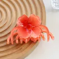 Close-up of translucent orange plumeria hair claw on a minimalist wooden tray - Orange Red