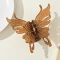 Macro detail of amber brown butterfly hair claw clip with golden metal spring - Brown