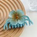 Detailed top view of a blue flower hair claw clip on a textured wooden tray with natural lighting - Blue