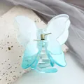Dettaglio macro di un fermaglio per capelli a farfalla blu sfumato con molla dorata - Blu