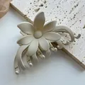 Close-up of a matte beige flower hair claw clip on a textured stone surface - Frosted 3D Flower / Off White